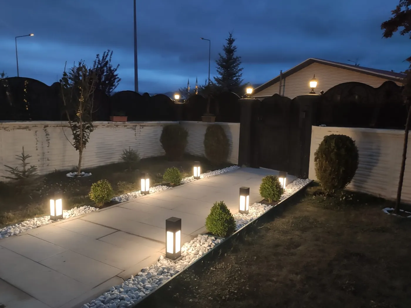 Warm bollard lights lining a garden path in front of a house at dusk